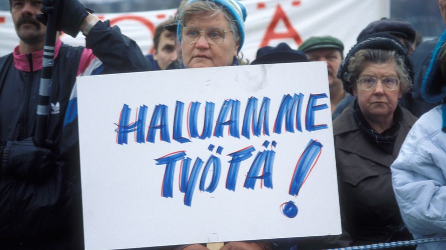 Työttömien mielenosoitus eduskuntatalon edessä Helsingissä marraskuussa 1993, nainen ja kyltti, jossa lukee "Haluamme työtä!".