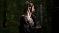 Lilly poseeraa kameralle varjoisessa metsässä.