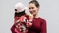 Lyhythiuksinen nainen ja lapsi asuinalueen leikkipaikalla.