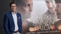 En man i kostym står bredvid en filmaffisch med texten "Hetki ennen valoa" och namn på skådespelare.