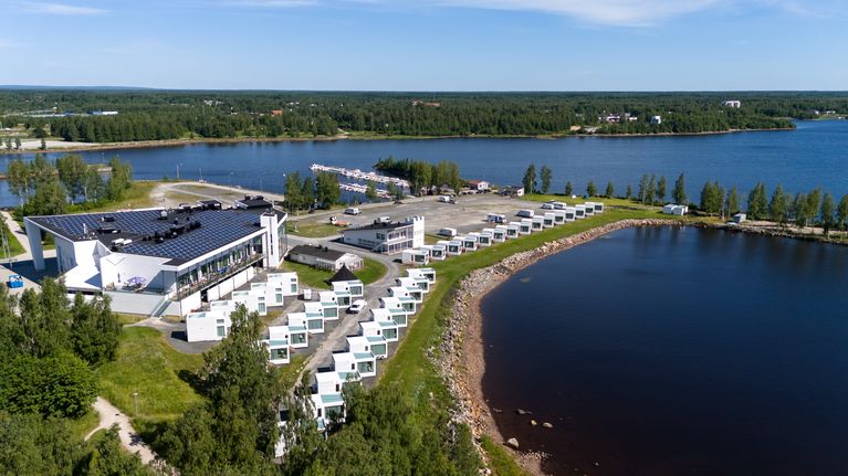 Ilmakuva Kemin ympärivuotisesta Lumilinnasta aurinkoisena kesäpäivänä, Lumilinnan takana lasihuviloita Perämeren rannalla.
