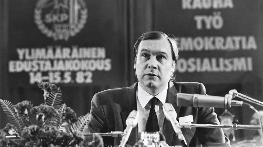 Kuvassa Seppo Toiviainen istuu ja puhuu puku päällään. Mustavalkokuva.