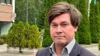 Ilkka Sasi seisoo ulkona. Taustalla näkyy vihreää puustoa ja lipputankoja.