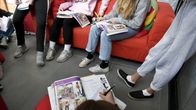 Oppilaita istuu sohvalla, lukien ja kirjoittaen oppikirjoihin.