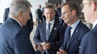 Four men in dark suits, standing in serious conversation. Niinistö, with back to camera, speaks while Kristersson listens.