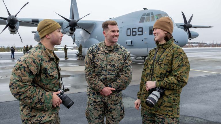 Maastoasuisia sotilaita, taustallaan  potkuriturbiini moottoreilla varustettu armeijan lentokone.