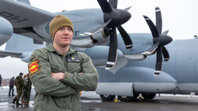 Lentäjä, taustallaan  potkuriturbiini moottoreilla varustettu armeijan lentokone.