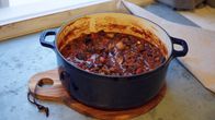 En svart gryta med chili sin carne på en köksbänk.