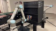 En automatisk robotarm lägger in en bok i en bokhylla. 