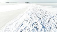 Talvinen maisema, jossa jää peittää merenpinnan, taustalla näkyy metsäinen saari.