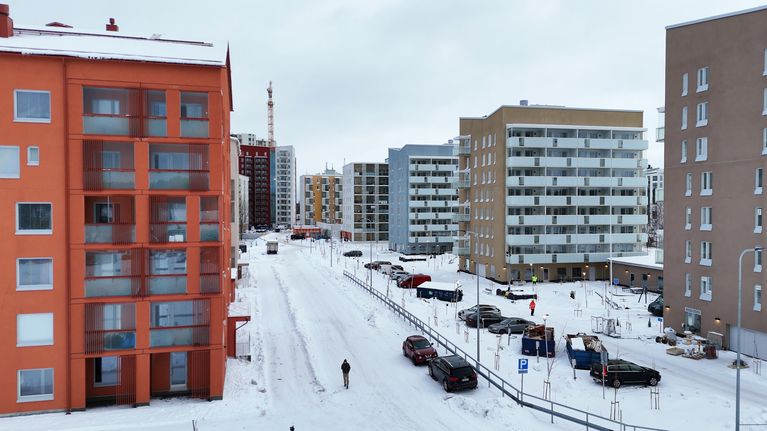 Katu, joka molemmilla puolilla kohoaa uusia kerrostaloja. Kadun päädyssä korkeimman kerrostalon takaa nousee nostokurki.