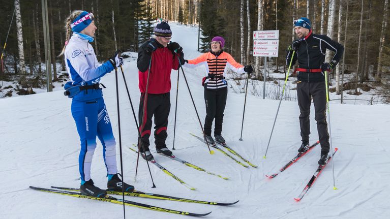 Hiihtäjät juttelevat ladunvarressa.