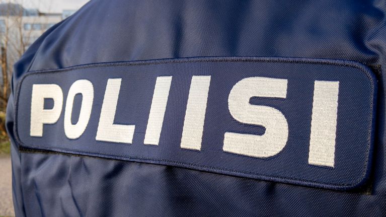Poliisi teksti poliisihenkilön selässä.