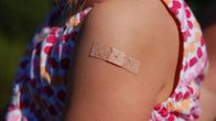 Ett barn med ett plåster på armen efter vaccination.