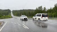 Two white cars are on the 62 on a rainy summer day.