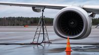 yleiskuva - Norwegian -halpalentoyhtiön kone lentokentällä. Lähikuvassa oikenapuoleinen suihkumoottori ja polttoaineen syöttöletku siipeen kiinnitettynä.