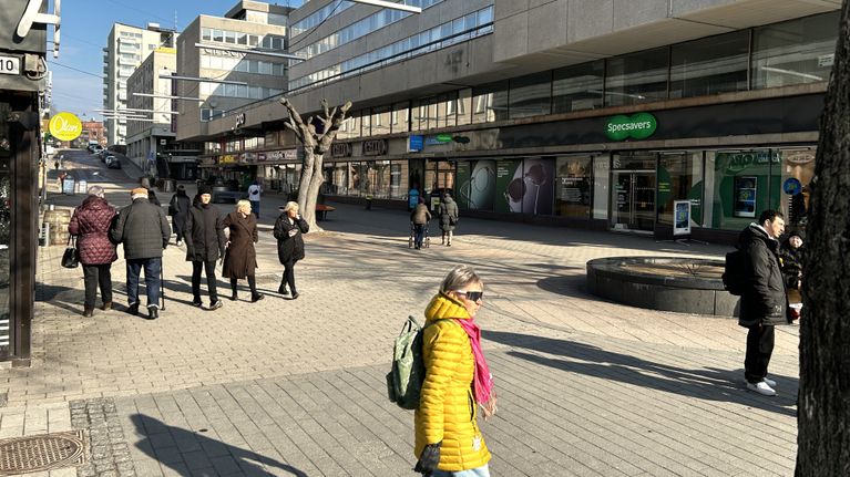 Kuvassa on aukea alue Lahden keskustassa. Ihmisiä kävelee alueella.
