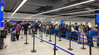 Many people standing in lines at an airport.