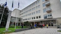 Ett stort grått hus med människor framför.