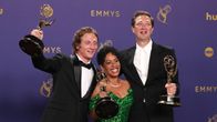 Jeremy Allen White,  Liza Colón-Zayas och Ebon Moss-Bachrach poserar med Emmystatyetter framför en lila vägg.