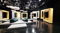 Studiotila, jossa on lavasteita ja katossa valoja, kaksi henkilöä selin taustalla.