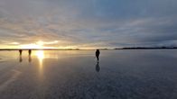 Tre långfärdsskrinnare på blank havsis.