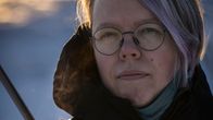 Valokuva henkilöstä, joka on pukeutunut lämpimästi ulkona kylmässä ympäristössä, jossa hengitys muuttuu höyryksi. Taustalla on luminen maisema.