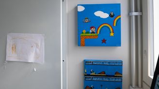 Seinälle on ripustettu värikkäitä peliaiheisia tauluja ja lapsen piirustus.