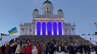 Helsingin tuomikirkon edusta on valaistu Ukrainan lipun väreillä. Portailla on paljon kynttilöitä.
