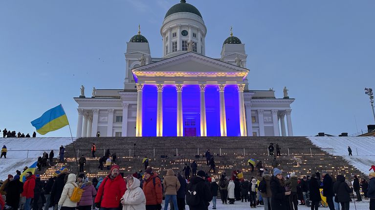 Helsingin tuomikirkon edusta on valaistu Ukrainan lipun väreillä. Portailla on paljon kynttilöitä.