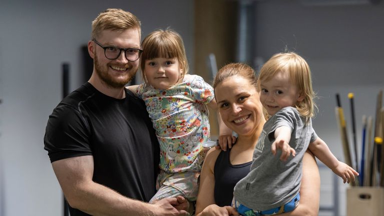 Aleksi Valtanen ja Elle Myllykoski pitävät sylissä lapsiaan ja katsovat kameraan.