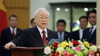 Nguyen Phu Trong seisoo puhujankorokkeella. Etualalla on värikkäitä kukkia.