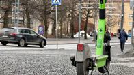 Vihreä sähköpotkulauta parkkeerattuna kadulle. Kadulla on paljon pientä soraa.