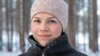 Nuori nainen katsoo kameraan ja hymyilee.