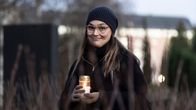 Teologi Anna Saurama hymyilee kameralle hautakynttilä käsissään.