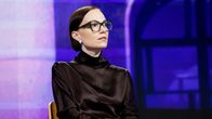 A woman in a brown bob and glasses, Minja Koskela, sits in a TV studio.
