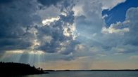 Storm clouds and rain over an island in the sea.
