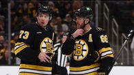 Charlie McAvoy ja David Pastrnak keskustelemassa jääkiekkokaukalossa varusteet päällä.