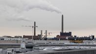 Helein Salmisaaren voimalaitosten yläosat ja piiput, jokta tupruttavat savua ilmaan. Kuvan alaosassa alueen rakennusten kattoja.