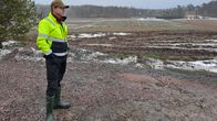 Man i gulsvarta kläder, keps och gummistövlar står vid en åkerkant.