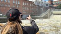Nuori nainen ottamassa kuvaa kuohuvasta Tammerkoskesta.