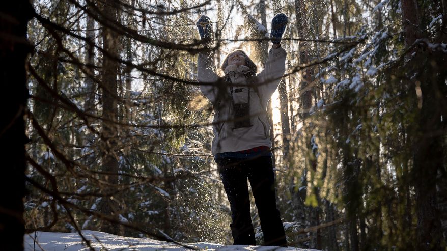 Kaarina Davis puiden keskellä suojelemassaan metsässä.