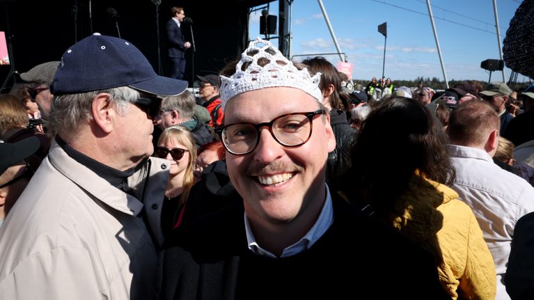 Henkilö hymyilee pukeutuneena virkattuun kruunuun.
