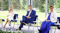 Kolme henkilöä istuu  mikrofonien vieressä sisätilassa.