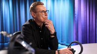 Presidentti Alexander Stubb kuulokkeet pöydällä edessään radiostudiossa.