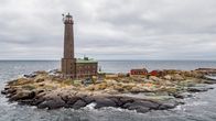 Bengtskärin majakka luodolla keskellä merta, pilvinen taivaanranta.