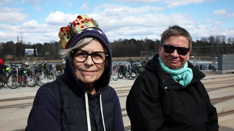 Kaksi henkilöä istuu sillankaiteella. Toisella henkilöistä on päässään kruunu.