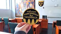 Keltaisella kirjailussa haalarimerkissä lukee "mieluummin puolangalla kuin taivasalla".