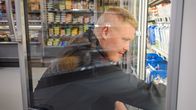 Eemeli Vinkka järjestelee tavaroita kaupan kylmäkaapissa.
