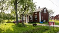 Vanha punainen pohjalaistalo pihamaineen kesäisessä maalaismaisemassa.